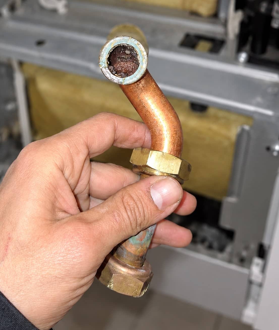 Tuyau en cuivre démonté d’une chaudière, presque entièrement bouché par des boues et du tartre