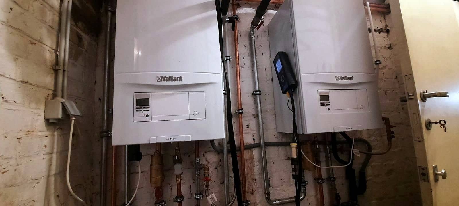 Deux chaudières murales Vaillant ecoTEC pro installées côte à côte dans une cave en briques peintes